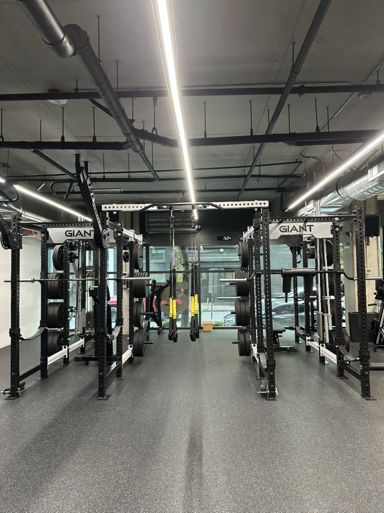 Two power racks facing each other with barbells and resistance bands at TRAIN Seattle's Independent Trainer Studio in Belltown