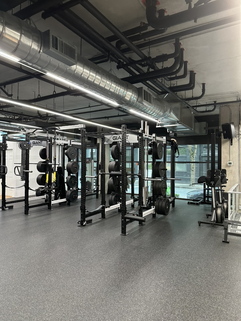 Row of squat racks loaded with weight plates on the open training floor at TRAIN Seattle's Independent Trainer Studio in Belltown