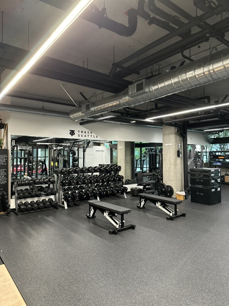 Dumbbell racks and flat benches beneath the TRAIN SEATTLE wall mark at the Independent Trainer Studio in Belltown