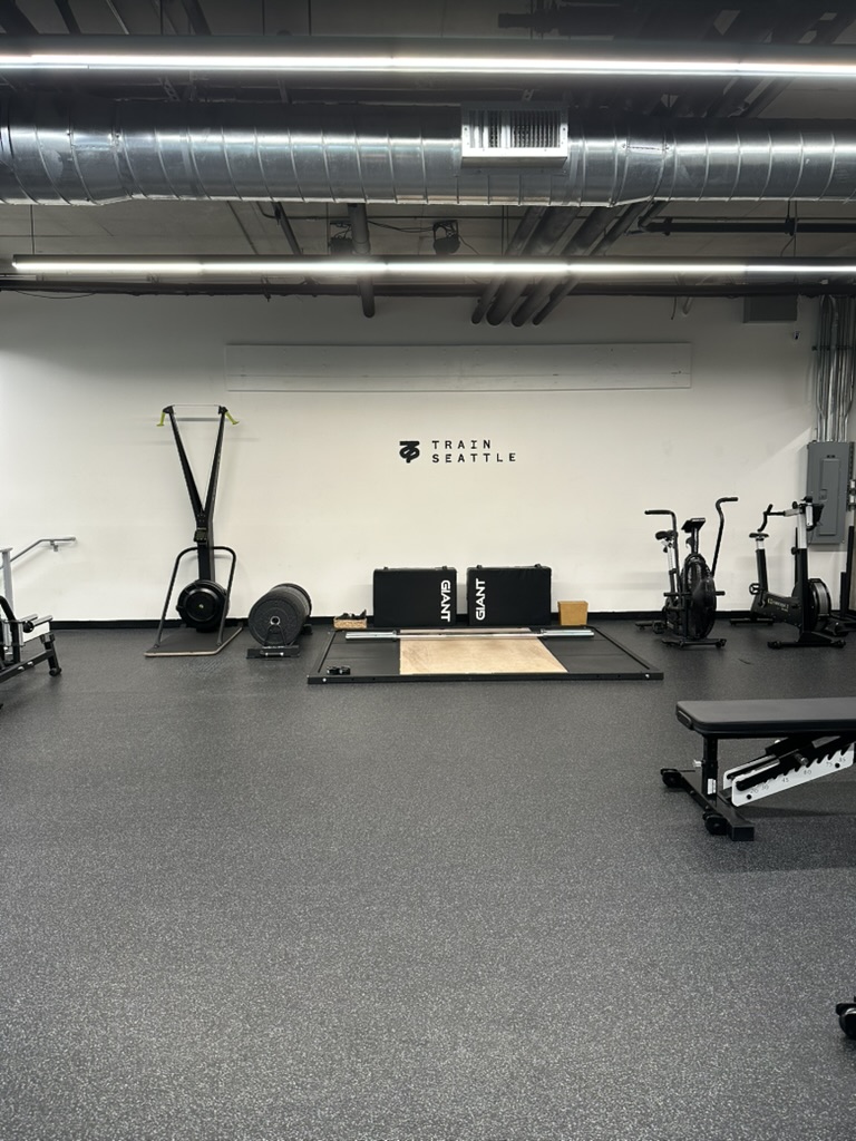 Quiet corner of the training floor with a ski trainer, plyo boxes and cardio bikes at the Belltown studio